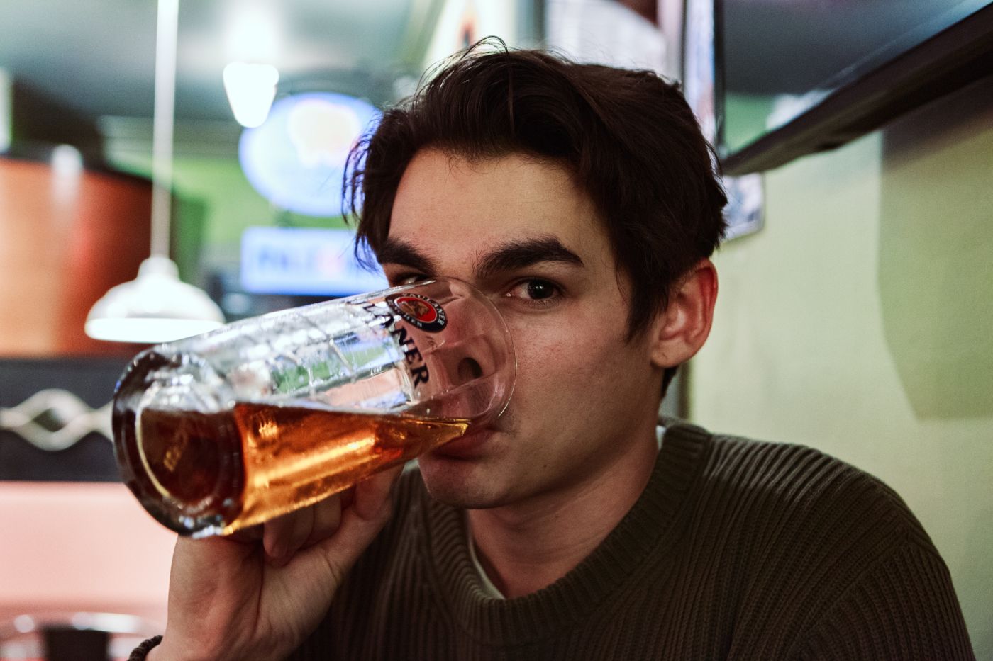 person drinking out of a glass mug