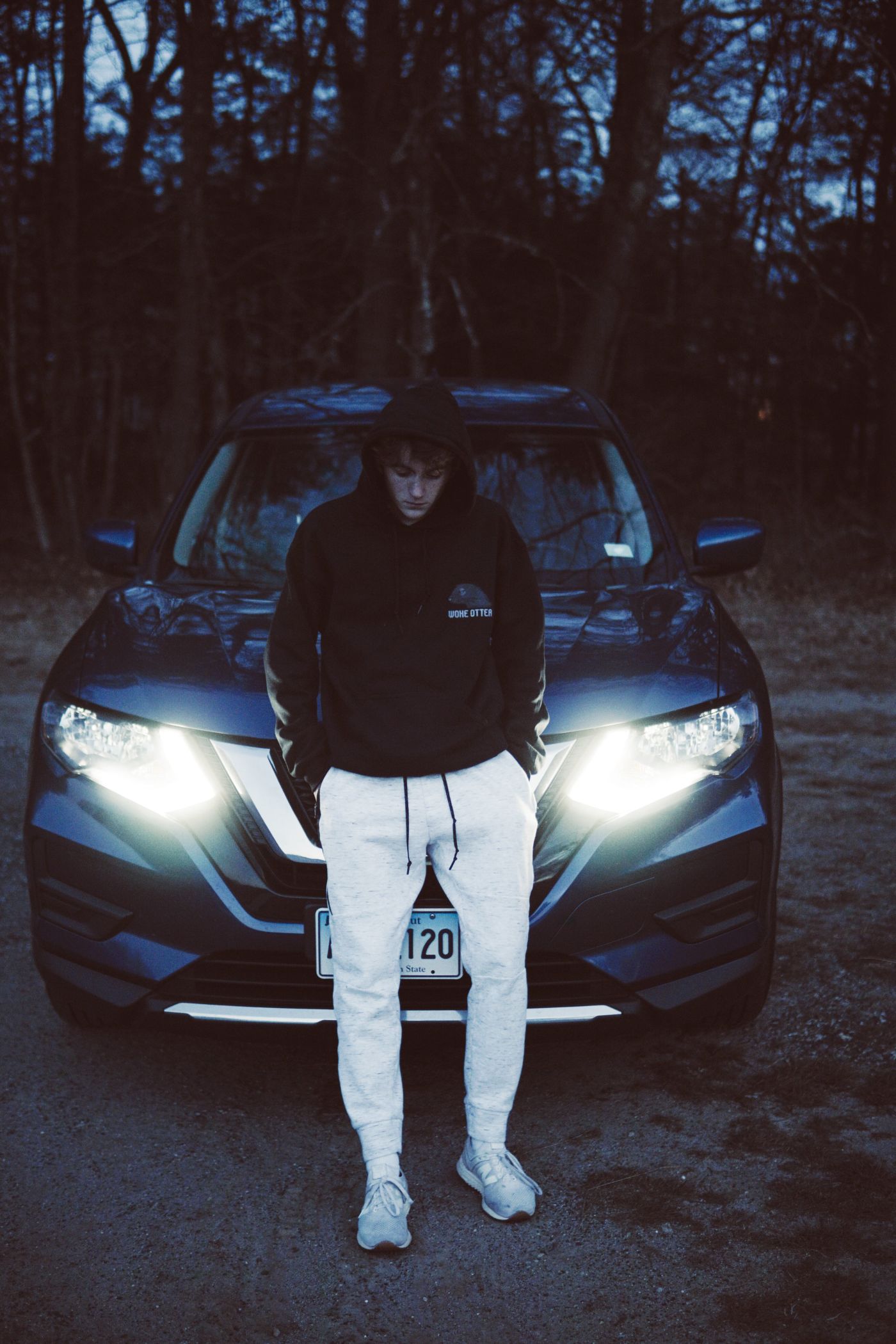 Person in sweats sitting on hood of car