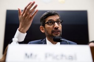 man at microphone talking with his hand raised